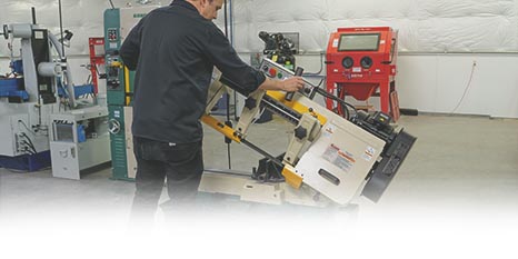 A person setting up a horizontal metal-cutting bandsaw for use