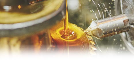a closeup of metalworking machine and workpiece covered in cutting oil while it makes a cut