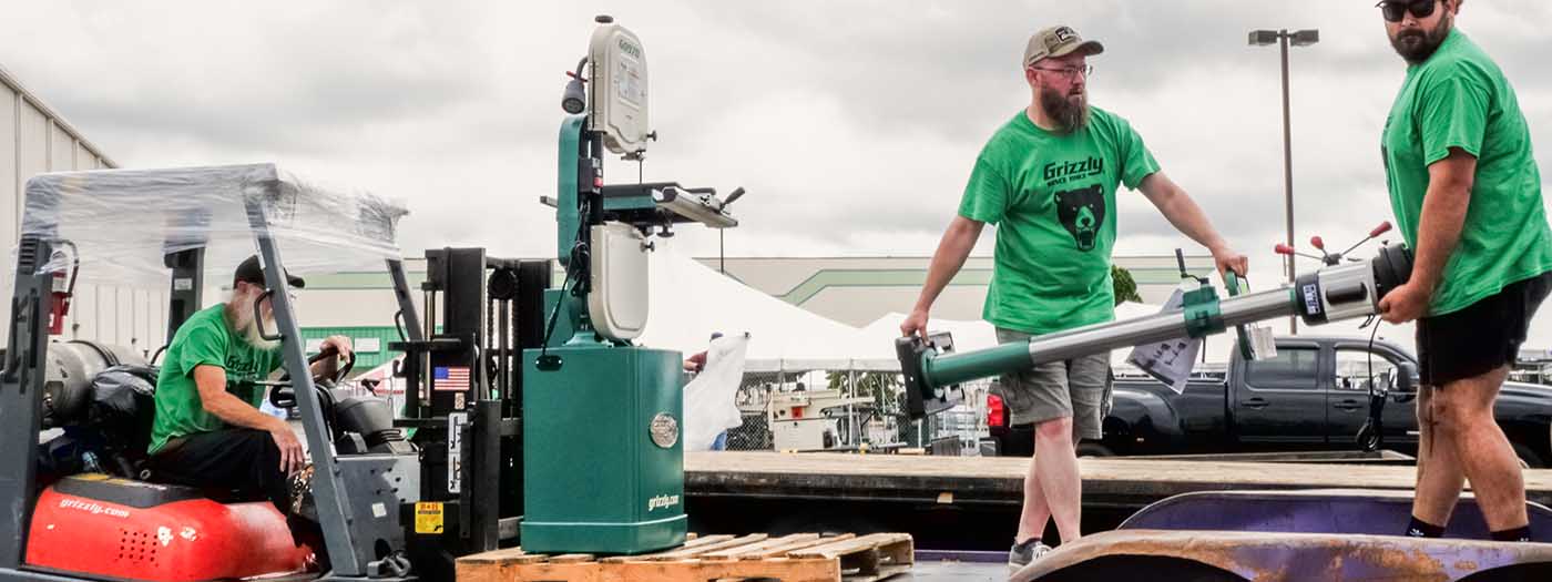 Grizzly employees load a bandsaw into a customer trailer